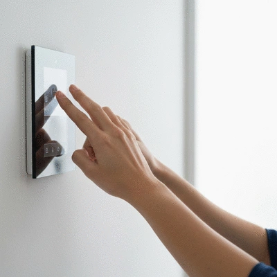 Person checking a modern thermostat on a wall